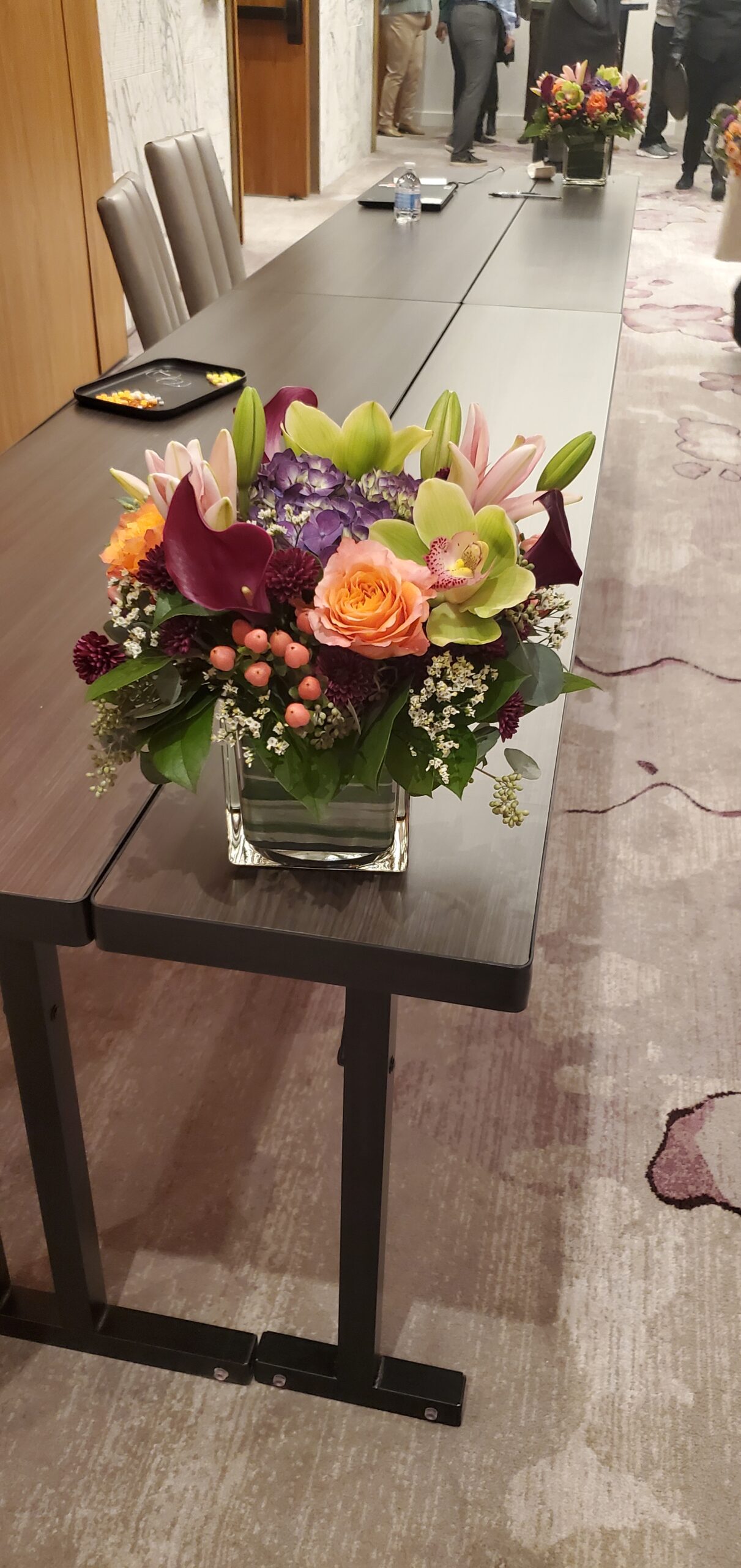 Artisan floral centerpiece on long conference table with bead craft trays