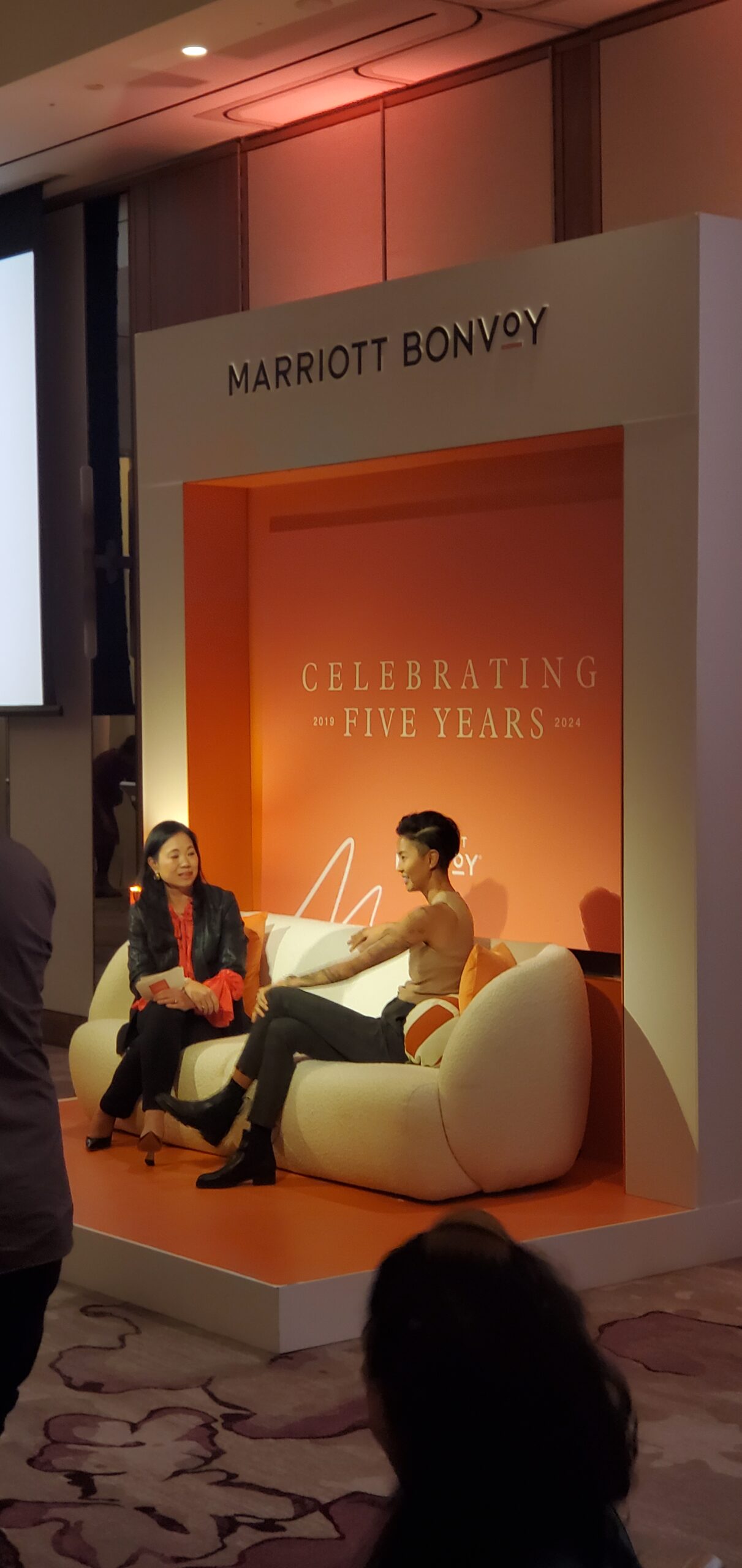 Kristen Kish and host in fireside chat on the cream bouclé sofa