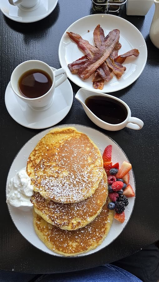 Fluffy buttermilk pancakes with fresh berries, crispy bacon, and coffee