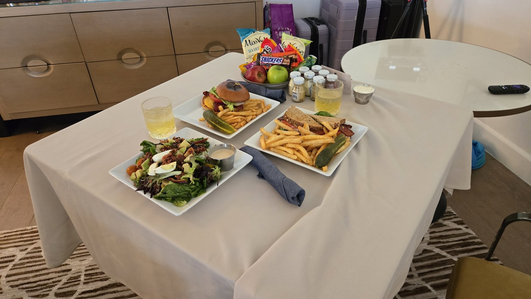 In-room dining spread featuring burgers, club sandwiches, salads, and welcome amenities