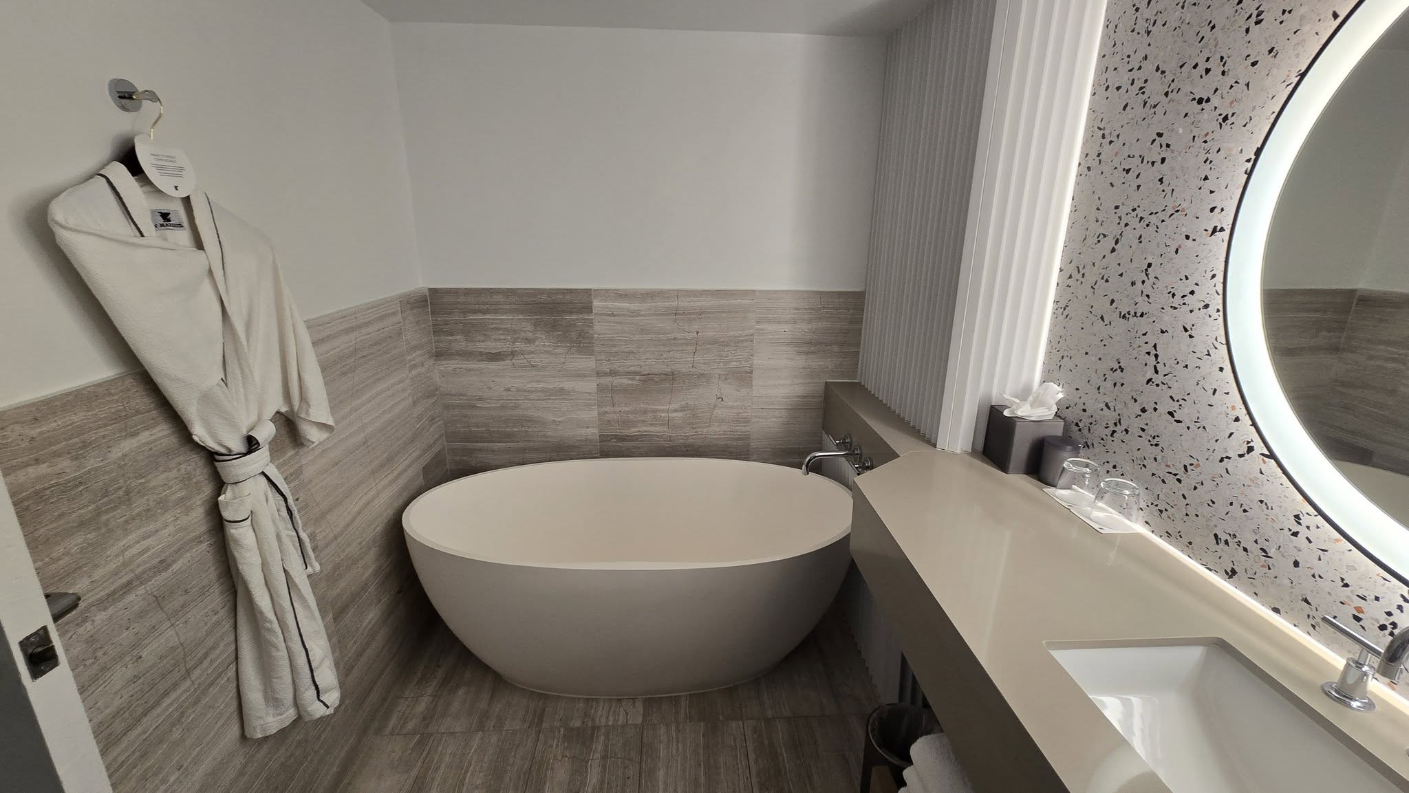 Suite view through sliding barn doors revealing freestanding oval tub and vanity