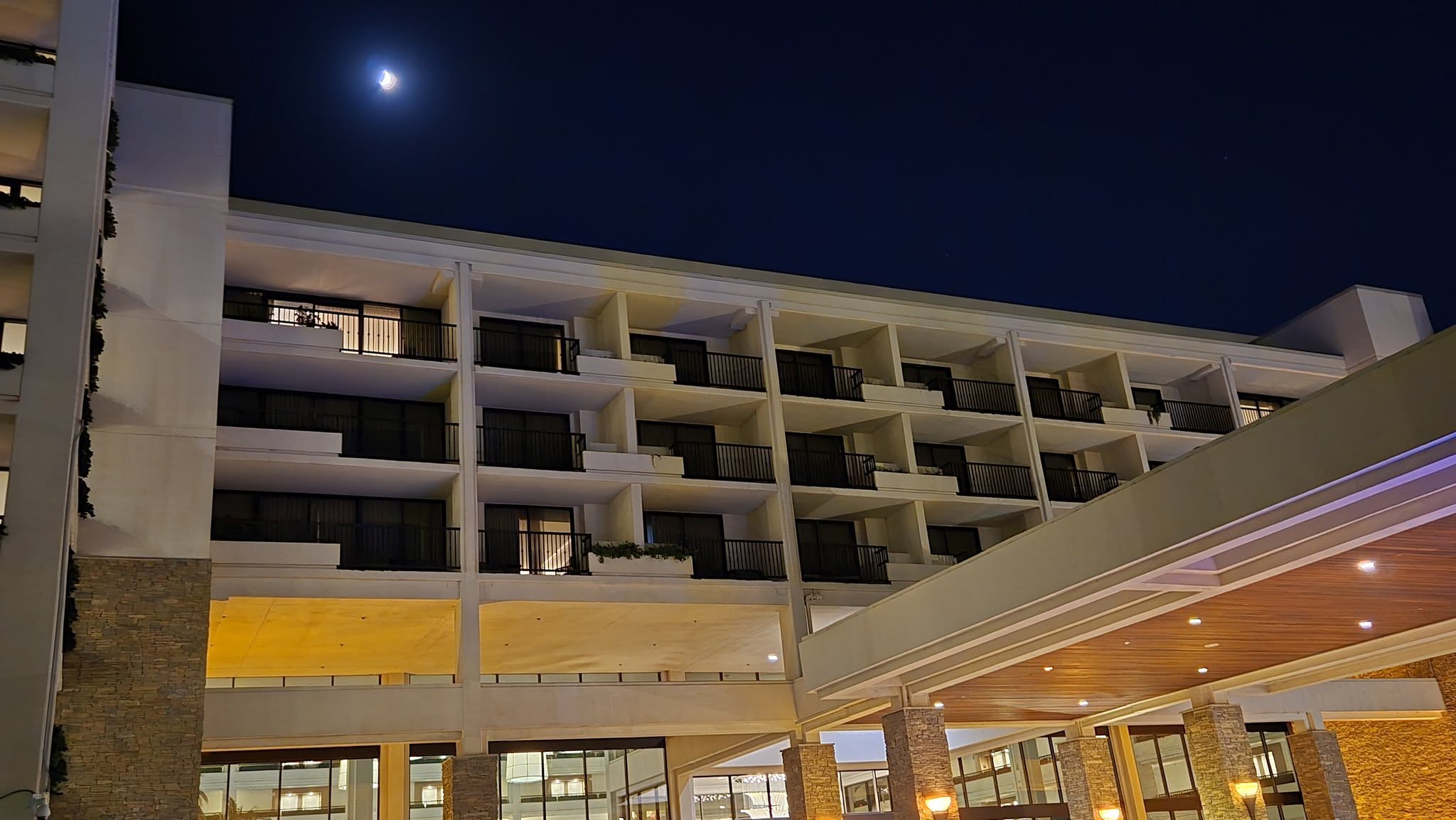 Porte-cochere grand entrance at night with cedar ceiling and stone pillars