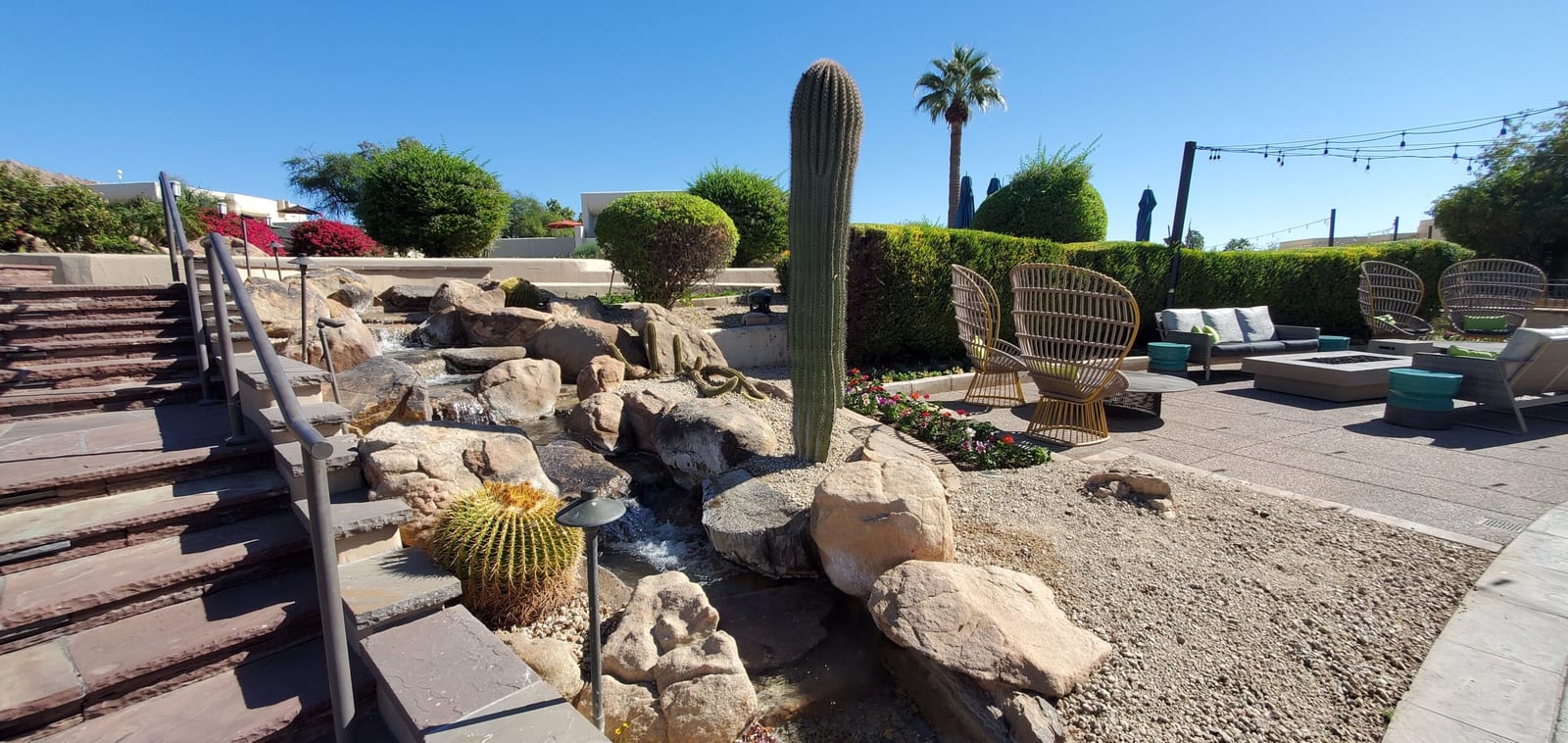 Desert waterfall stream flowing past wicker lounge chairs and palm trees