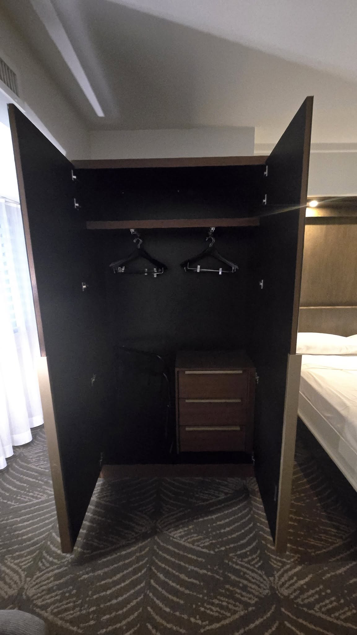 Suite wardrobe closet featuring electronic safe, drawers, and luggage storage