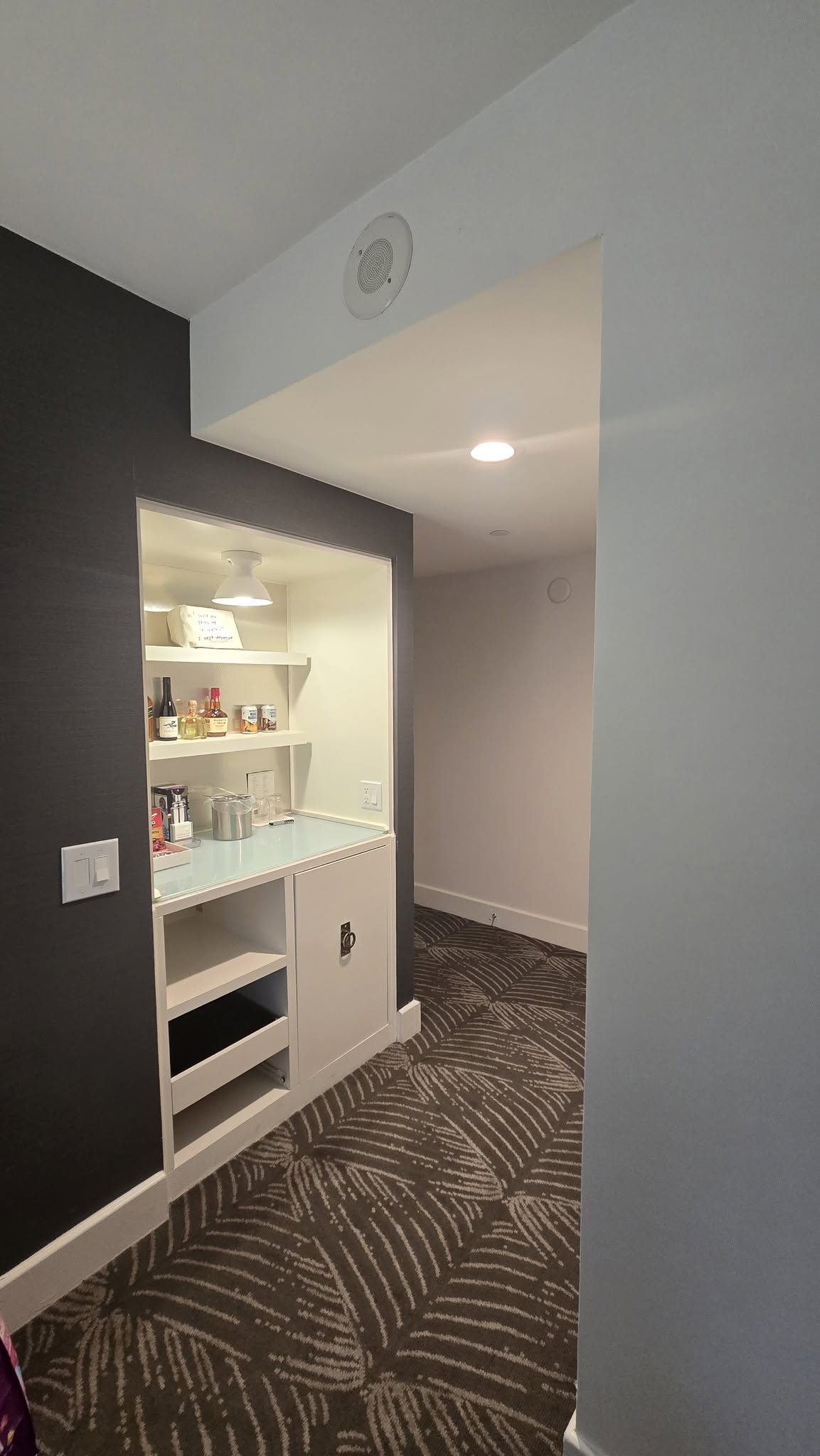 Recessed dry bar niche with glassware, cocktail shaker, and spirits