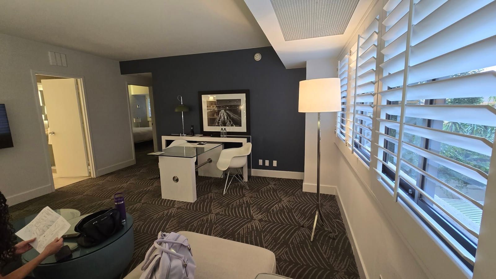 Suite living parlor overview showing sectional couch, glass desk, and modern lighting